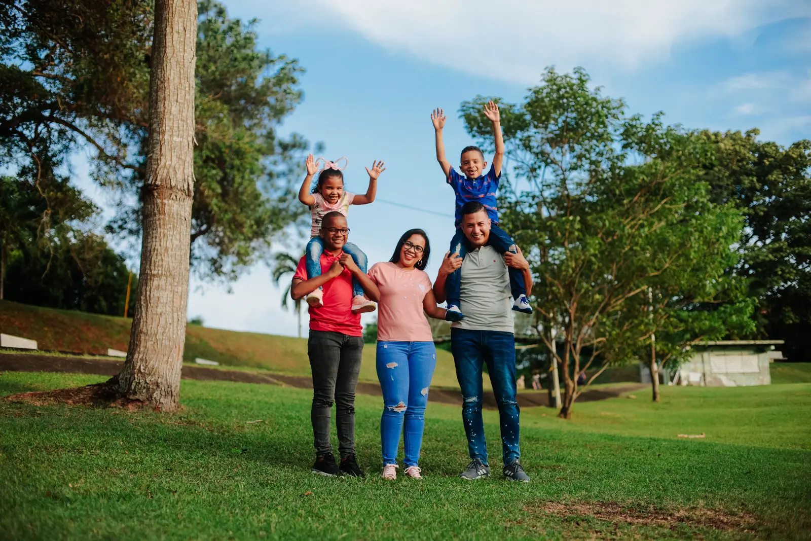 Família com pai, mãe e dois filhos sorrindo juntos em um parque
